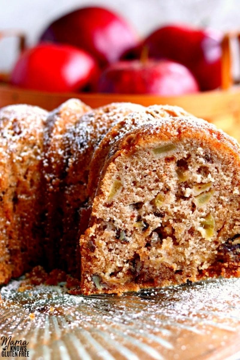 gluten-free apple cake sliced on a cake plate with apples in the background