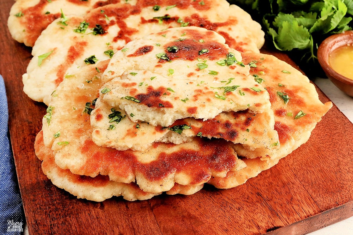 gluten-free naan bread torni n half to show the texture on a wooden cutting board