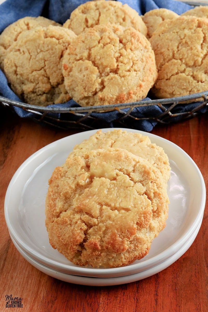 almond flour biscuits on a white plate with the basket of biscuits in the background