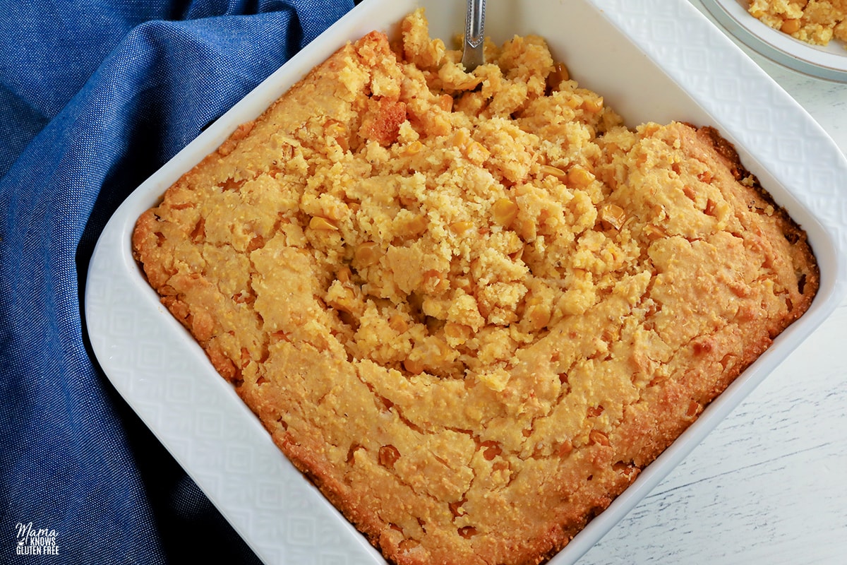 gluten-free corn casserole in a white baking dish with a silver spoon