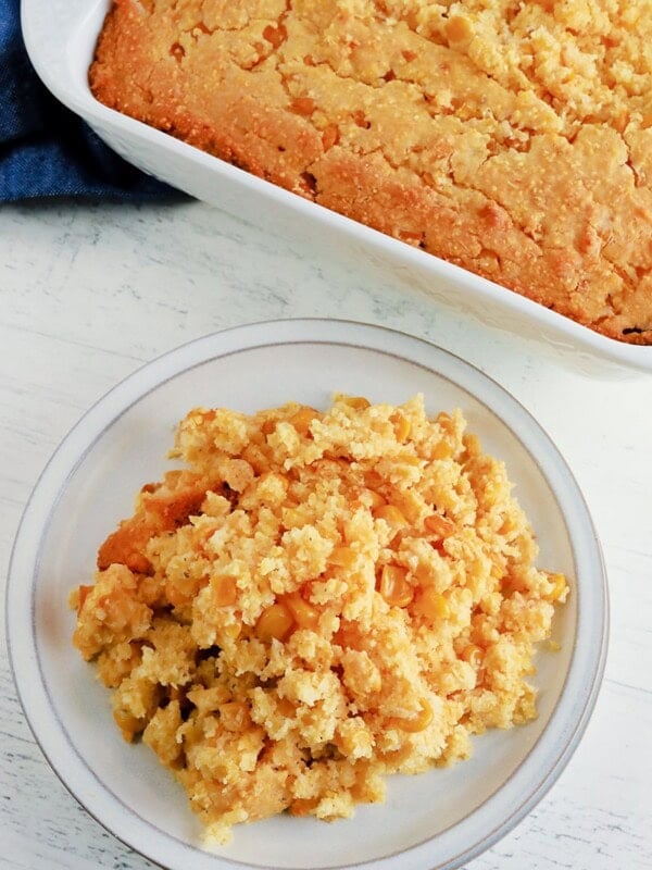 gluten-free corn casserole serving on a white plate with the casserole in the background