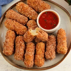 gluten-free mozzarella sticks on white plate with a side of marinara sauce