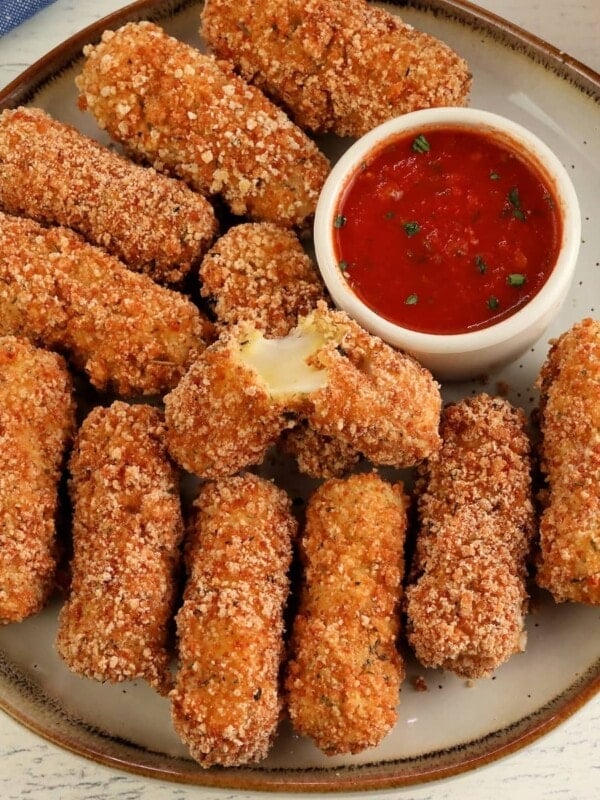 gluten-free mozzarella sticks on white plate with a side of marinara sauce