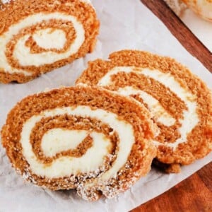 gluten-free pumpkin roll slices on parchment paper on a wood cutting board