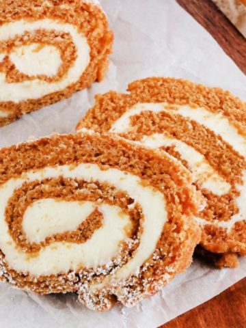 gluten-free pumpkin roll slices on parchment paper on a wood cutting board