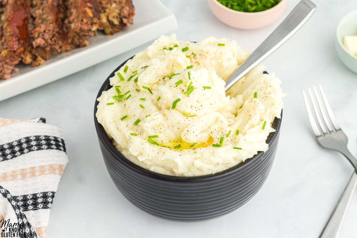 gluten-free mashed potatoes in a back owl with a serving spoon.