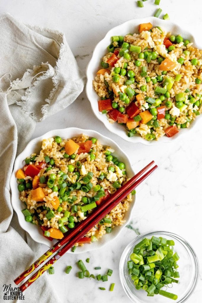 Two bowls of Gluten-Free Fried Rice with some scallions in a separate bowl.