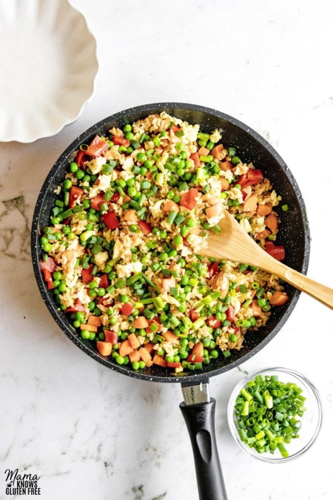 Gluten-Free Fried Rice in a frying pan with some scallions in a bowl beside it.