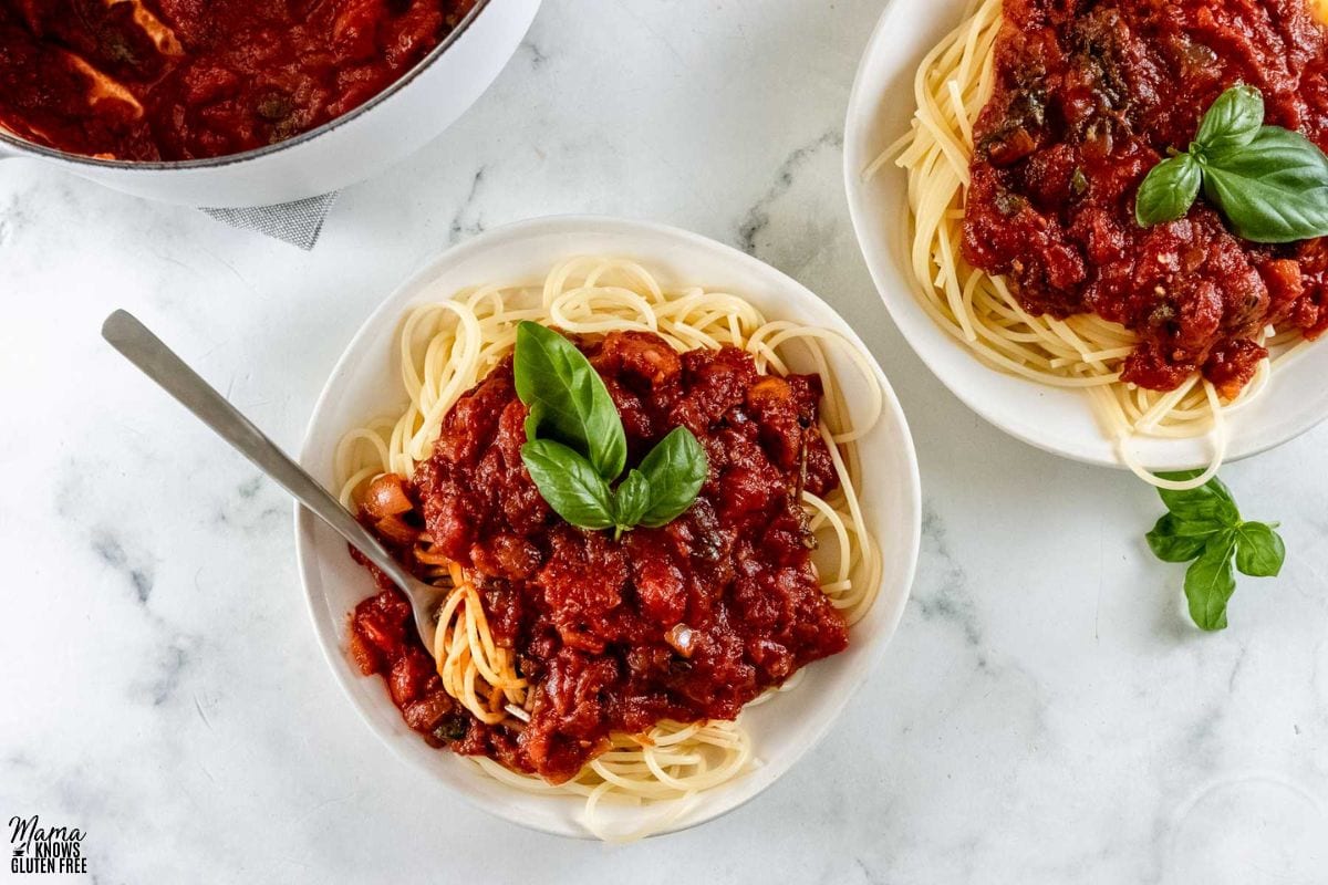 gluten-free spaghetti sauce along with spaghetti in bowls with fresh basil on top