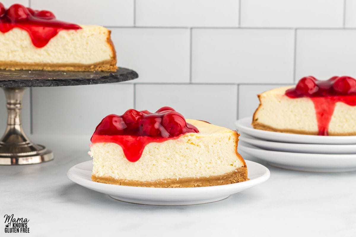 Gluten-free cheesecake on a plate, with another plate with cake and a cake dish in the background.