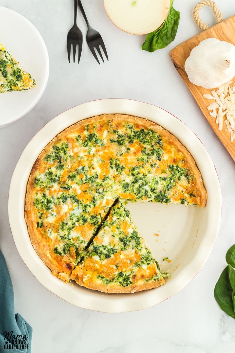 Gluten-free spinach quiche with one slice missing.