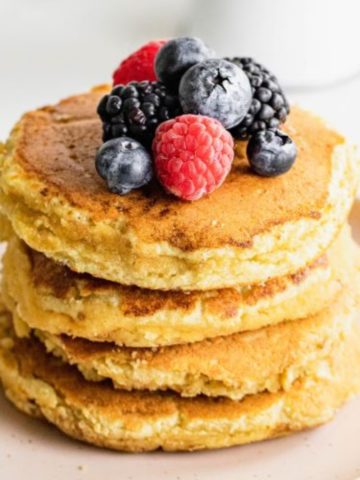 almond flour pancakes stacked on a plate topped with berries