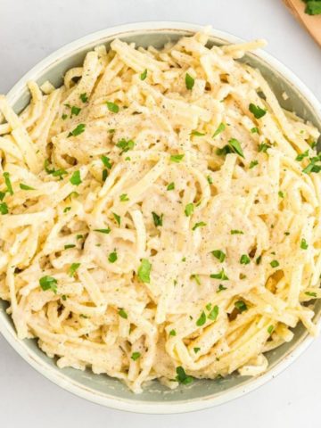 gluten-free Alfredo sauce and pasta in a bowl topped with parsley