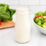 dairy-free ranch dressing in a glass bottle with a salad in the background