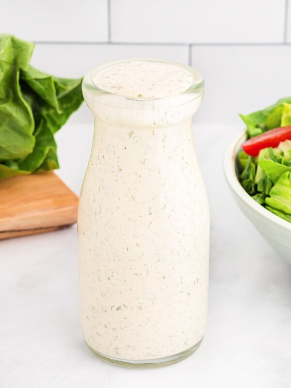 dairy-free ranch dressing in a glass bottle with a salad in the background