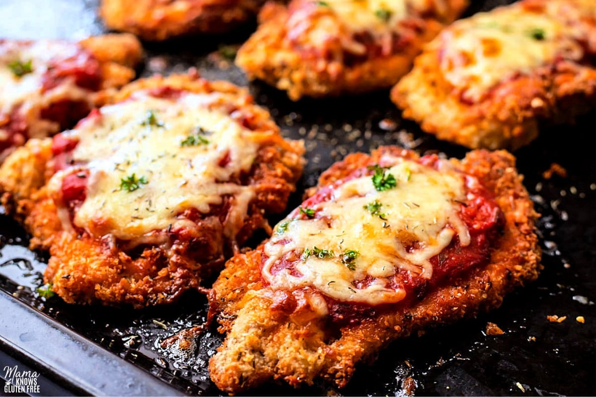 gluten-free chicken parmesan baked on a black baking sheet