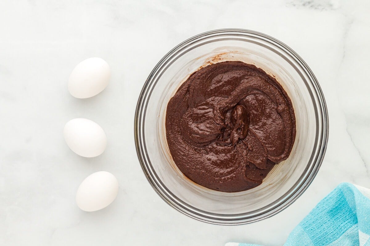 Sugar added to melted chocolate in a glass mixing bowl.