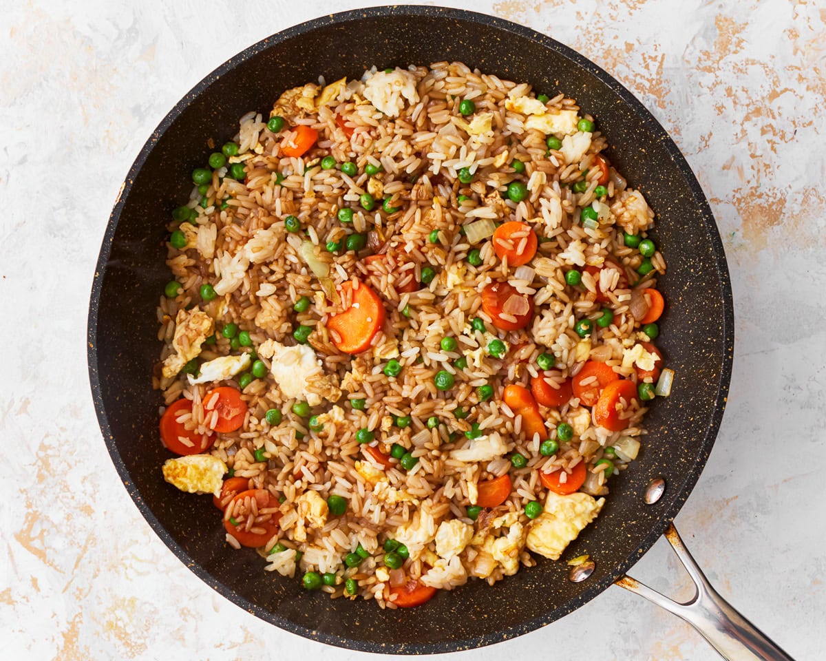 Soy sauce added to gluten-free fried rice in a skillet