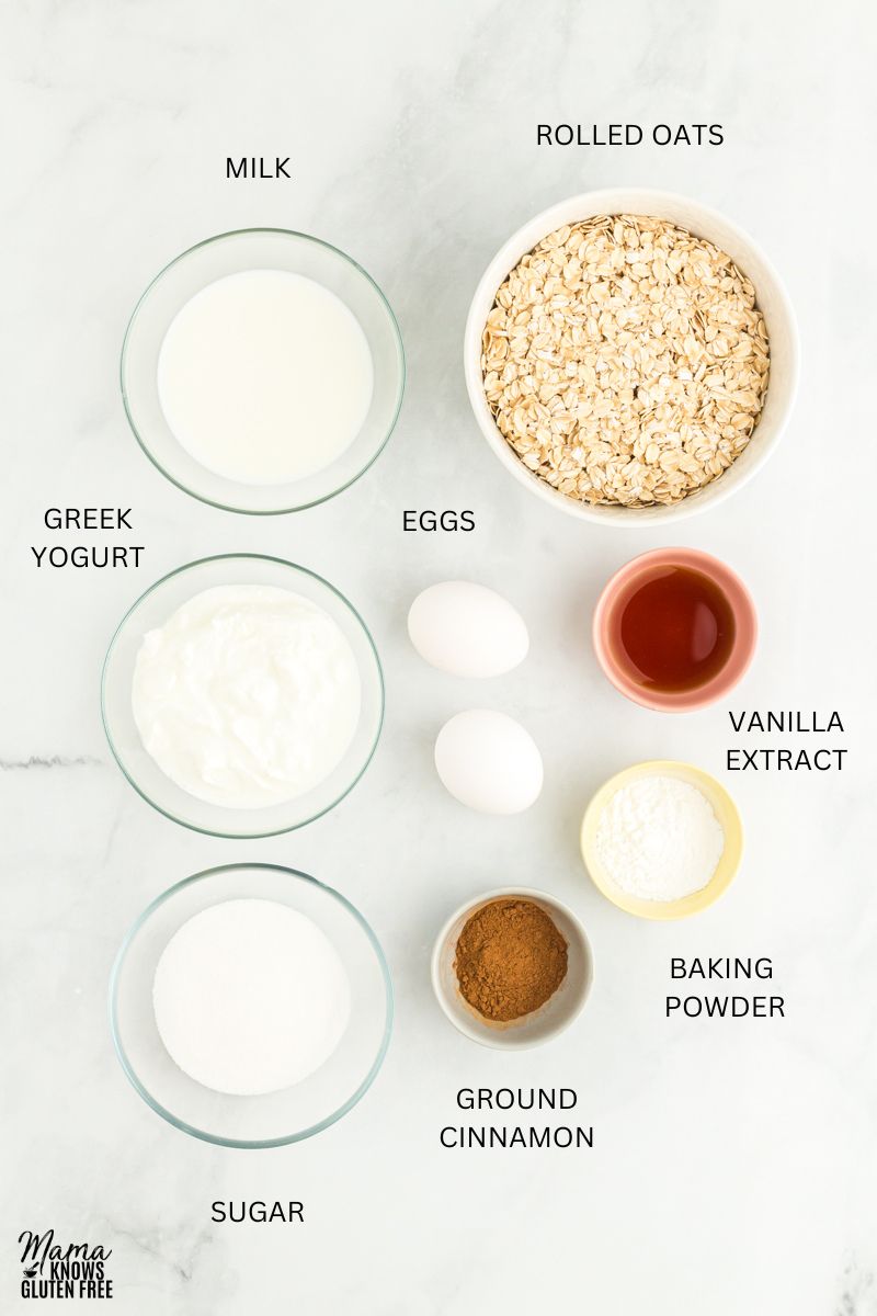 Ingredients for oatmeal pancakes measured in cups and bowls on marble surface