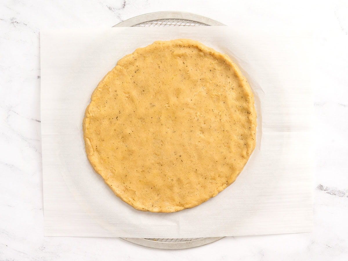 Almond flour pizza dough rolled into a thin circle on parchment paper