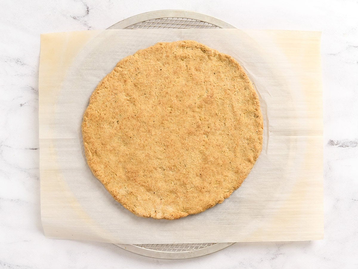 Pre-baked almond flour pizza crust, golden and firm, on parchment paper