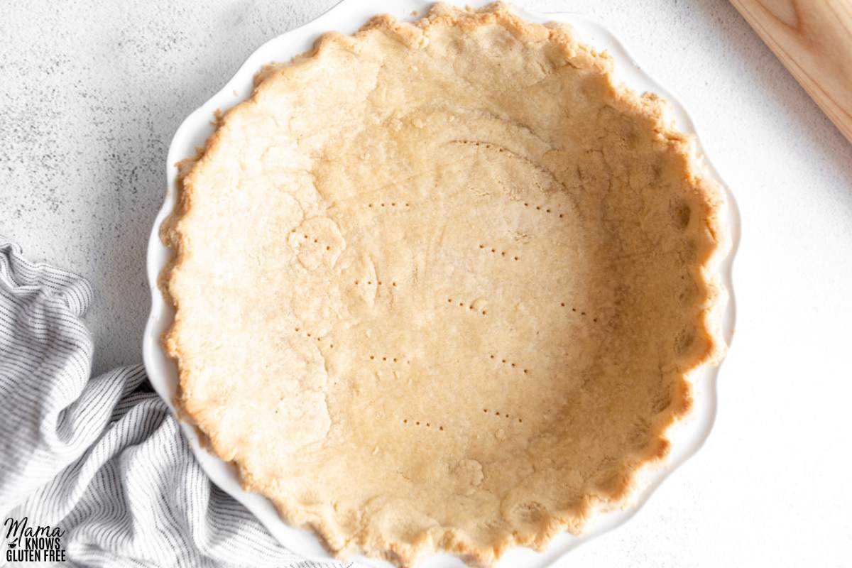 Gluten-Free Almond Flour Pie Crust in white pie plate with striped towel.