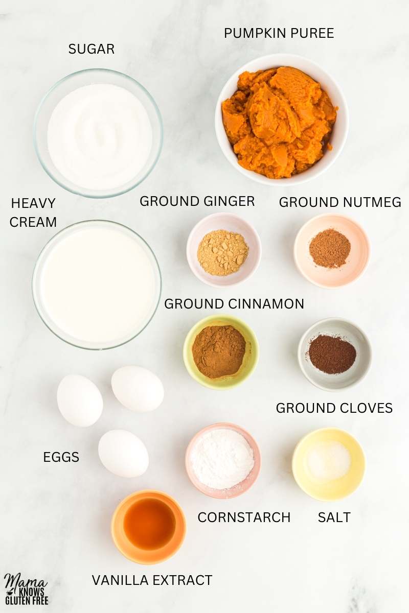 Ingredients for Gluten-Free Crustless Pumpkin Pie measured in bowls and cups on marble surface.
