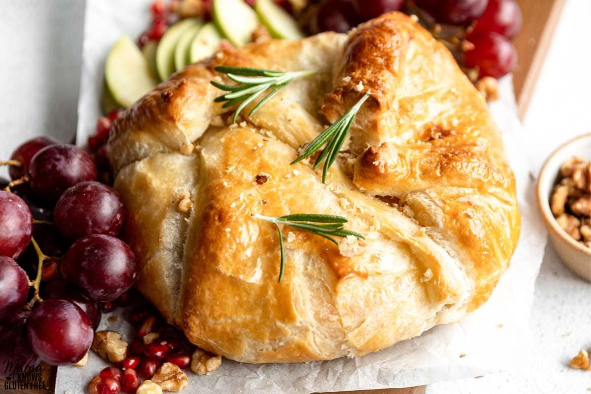 Close up shot of Gluten-Free Baked Brie surrounded by grapes and apple slices.