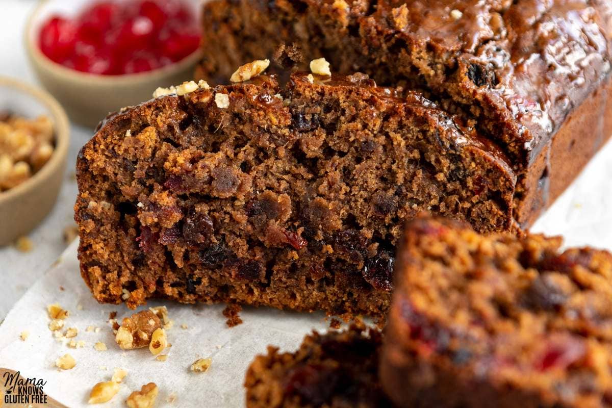 Close up of a slice of Gluten-Free Fruit Cake with candied cherries in the background.