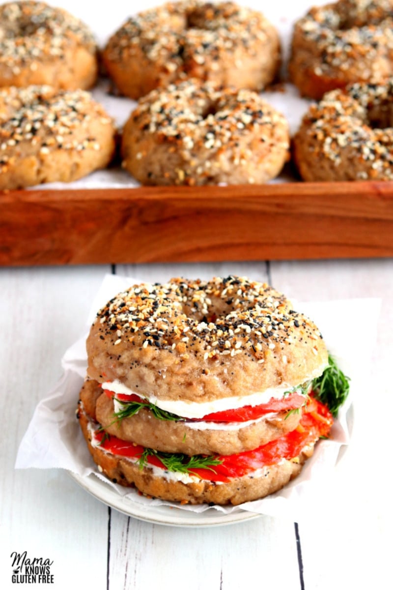 gluten-free bagel with locks and cream cheese on a white plate with the bagels in the background