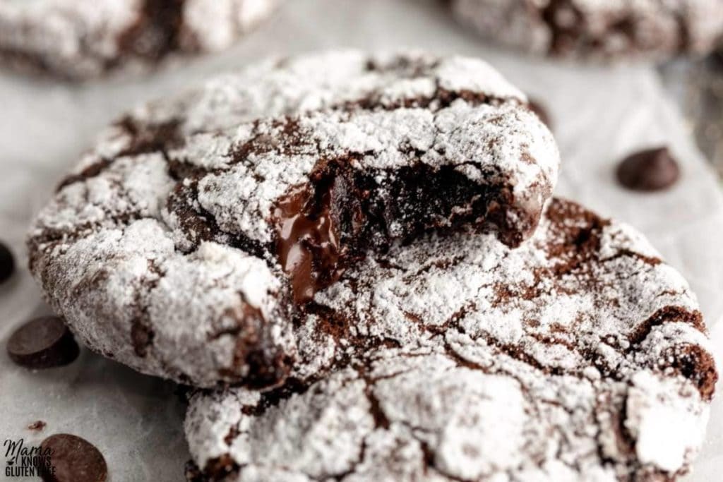 gluten-free chocolate crinkle cookies stacked on a white parchment paper
