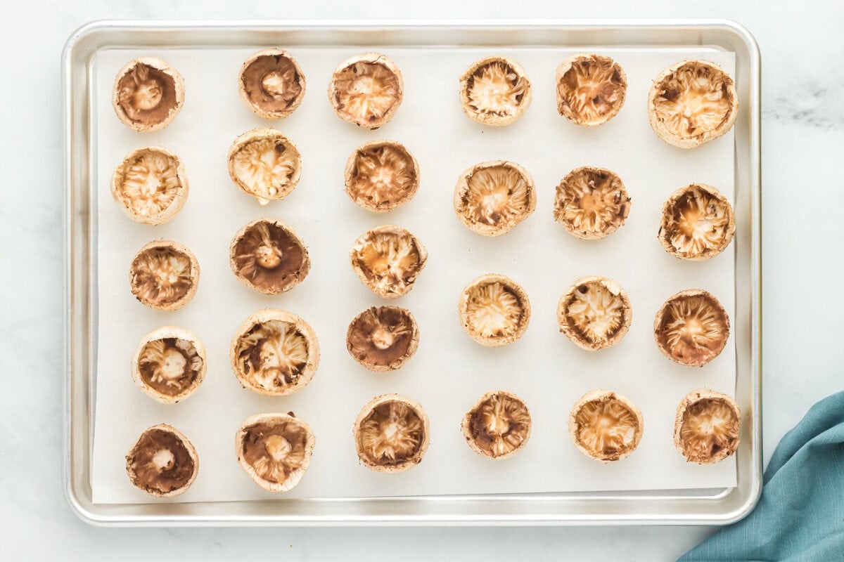 Mushroom caps on a parchment lined baking sheet.