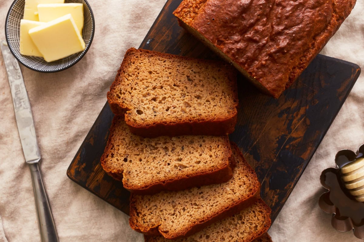 overhead view of a partially cut loaf of almond flour bread with splayed slices on a cutting board.