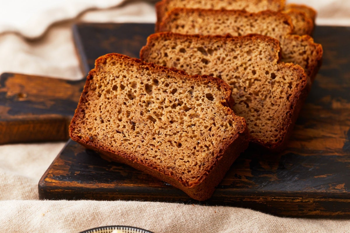 Slices of almond flour bread leaning on a cutting board.