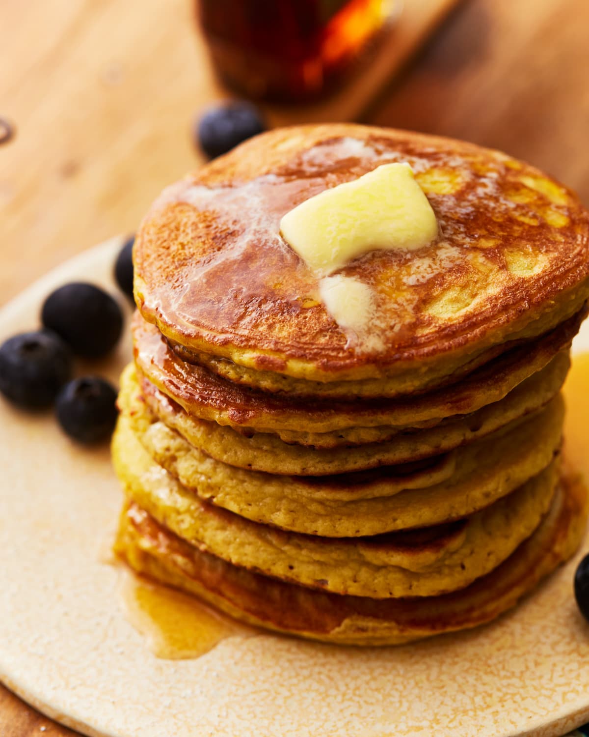 coconut flour pancakes stacked on a plate with butter and blueberries.