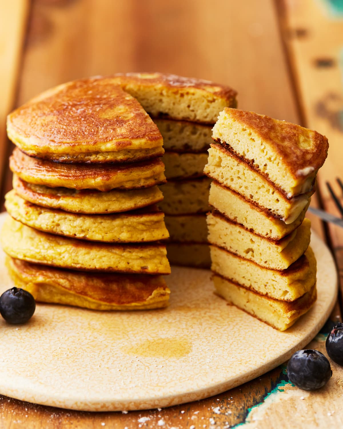 coconut flour pancakes stacked on a plate with a wedge cut out to show the texture.