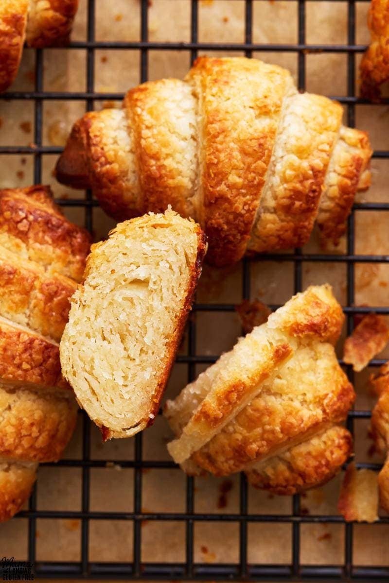 gluten-free croissants on a cooling rack with one sliced to show the texture