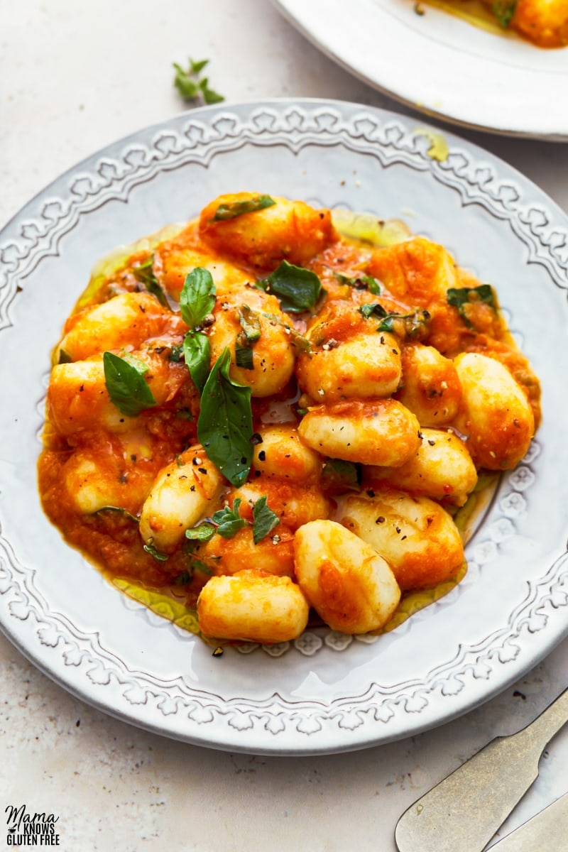 gluten-free gnocchi in tomato sauce in a white bowl topped with basil