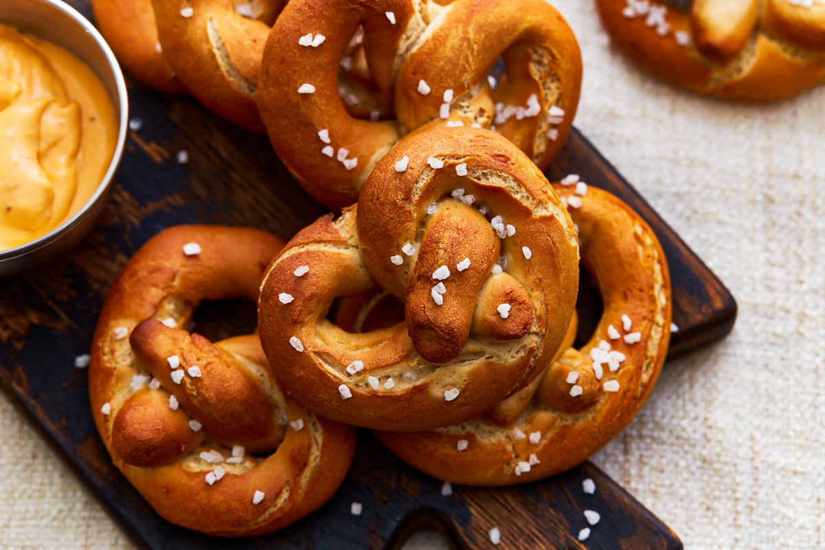 Gluten-free soft pretzels stacked on a cutting board.