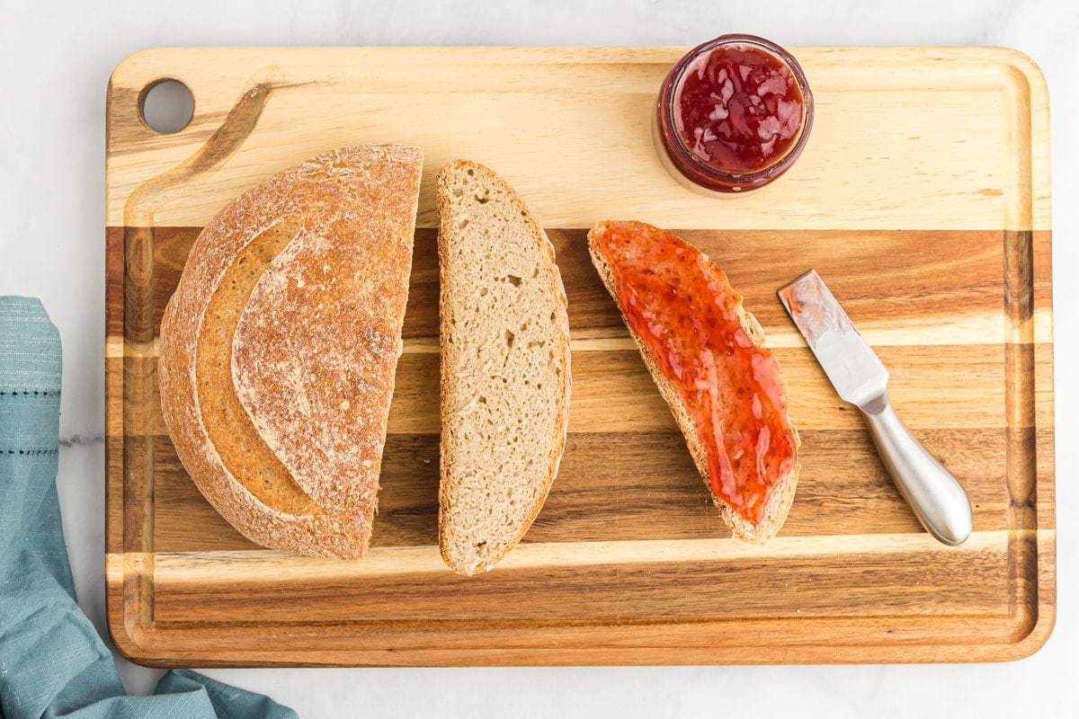 gluten-free sourdough loaf sliced on a wood cutting board with jam  gluten-free sourdough loaf sliced on a wood cutting board with jam and a knife.
