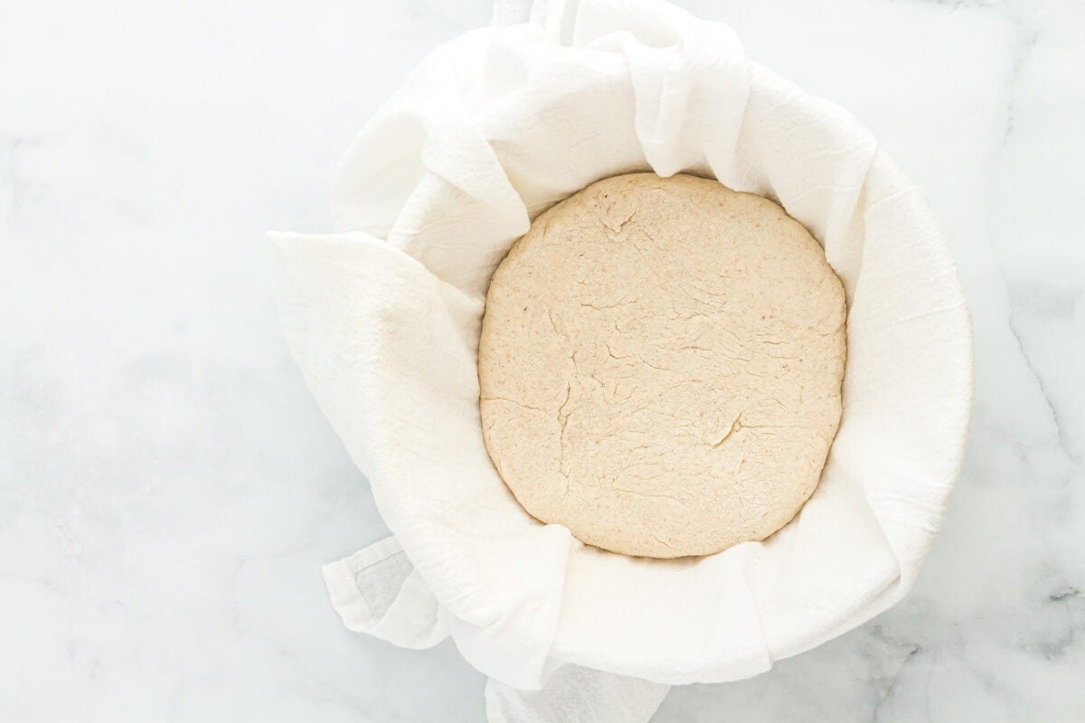 gluten-free sourdough bread dough in a bowl lined with cloth.