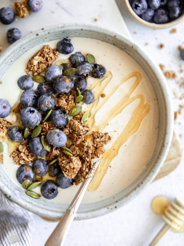 coconut yogurt in a white bowl topped with granola and fruit.