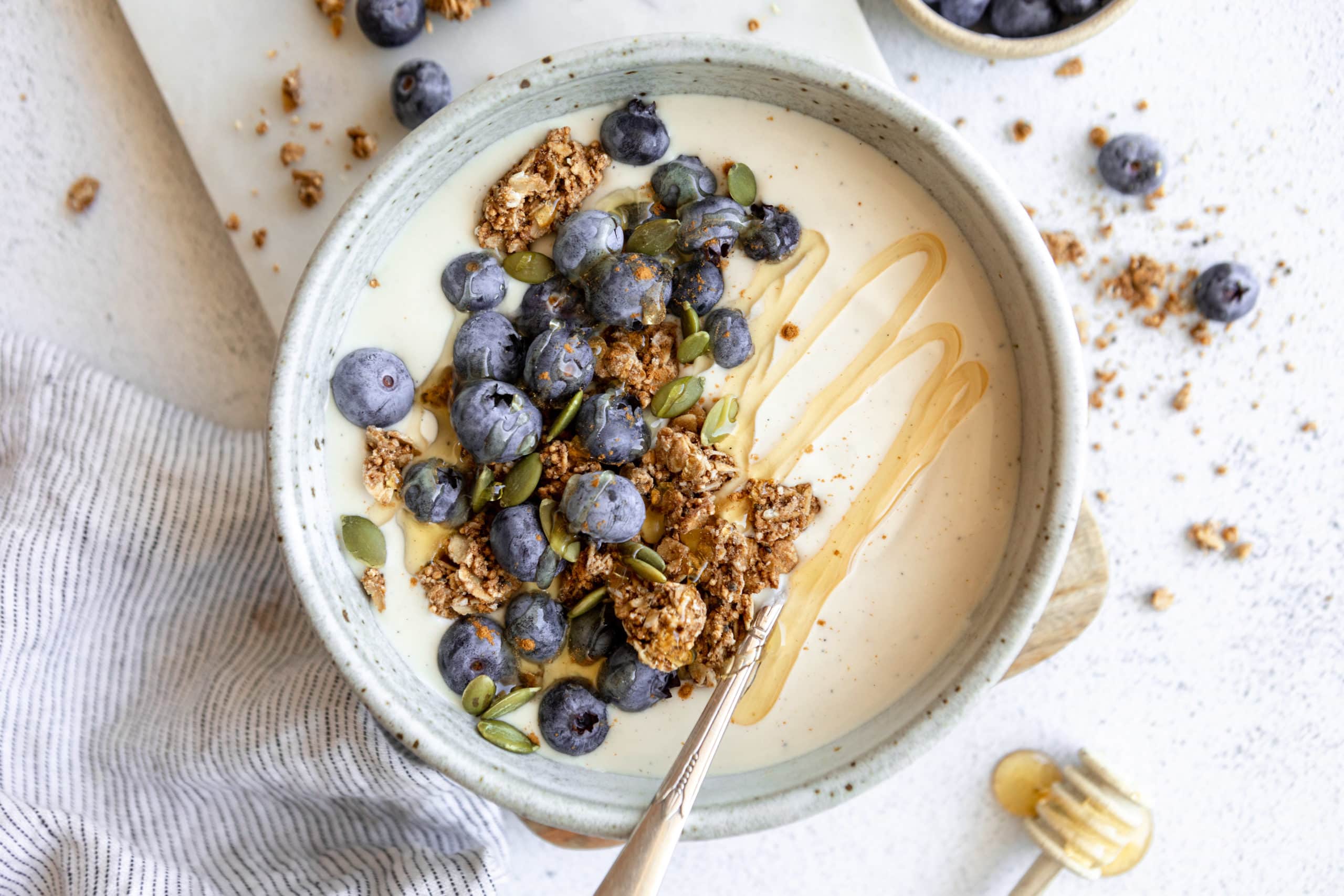 coconut yogurt in a white bowl topped with granola and fruit.
