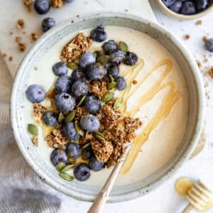 coconut yogurt in a white bowl topped with granola and fruit.