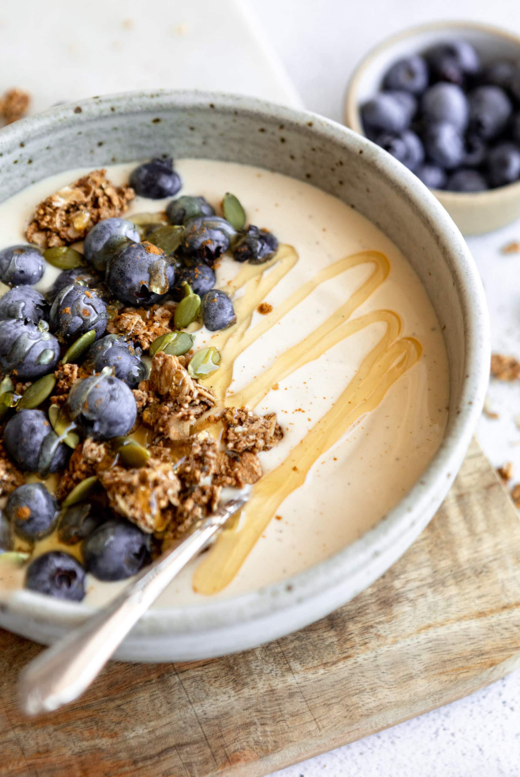 coconut yogurt in a white bowl topped with granola and fruit.