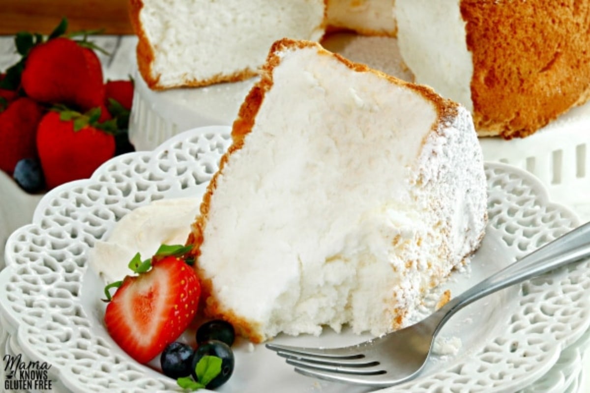 gluten-free angel food cake slice on a white plate with berries and a fork