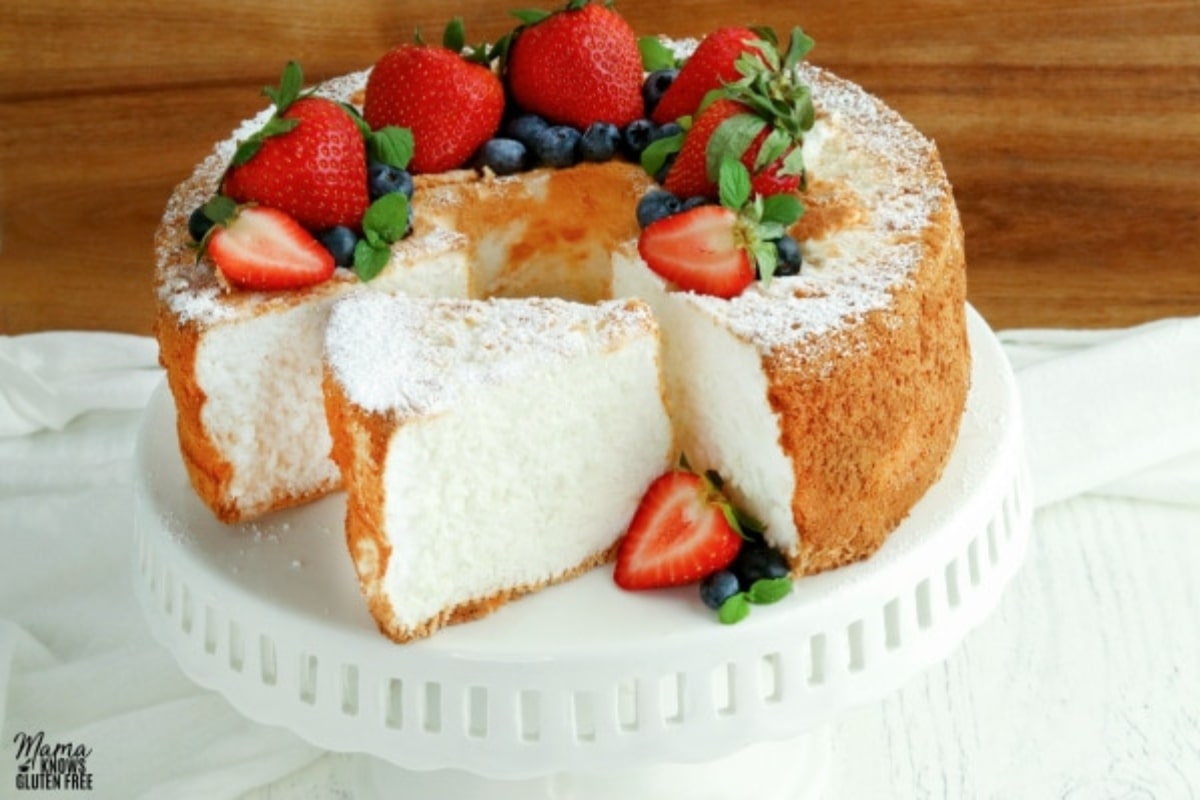 gluten-free angle food cake on a white cake plate topped with berries