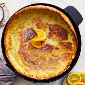 overhead view of a gluten-free dutch baby in a pan with an orange slice.