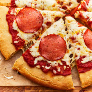 partial overhead view of a sliced gluten-free pepperoni pizza.