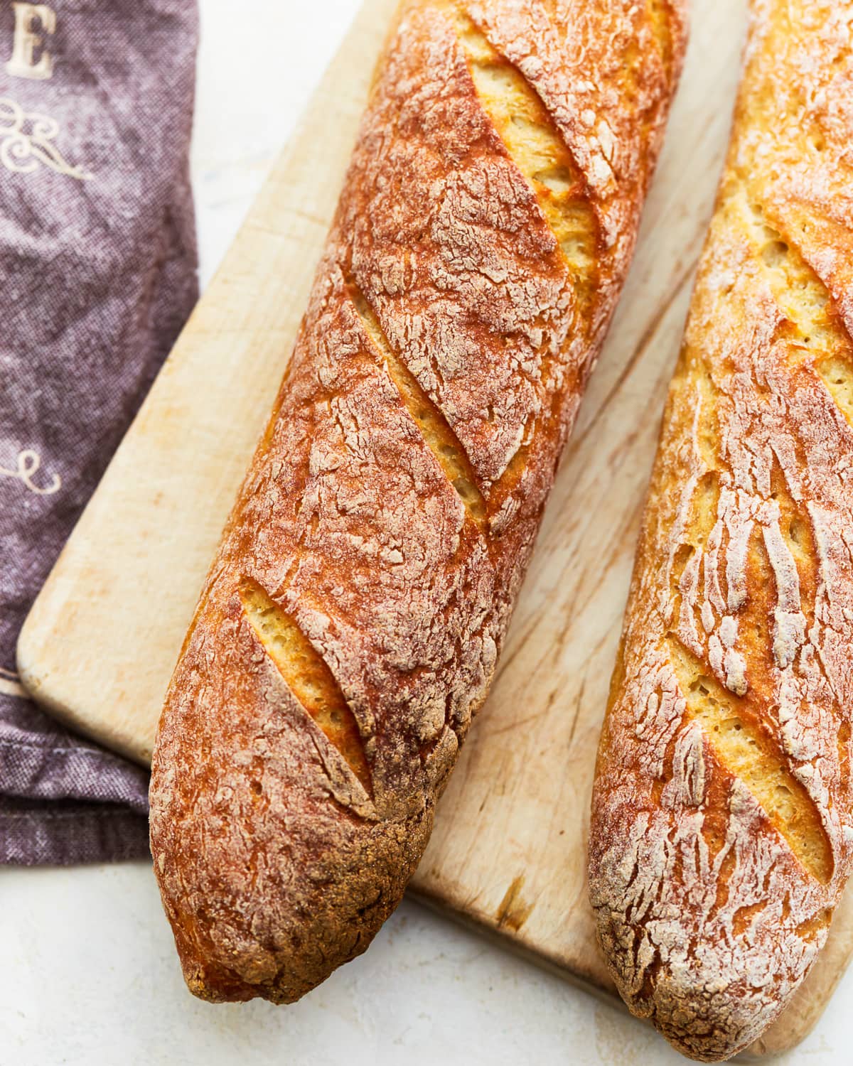 close-up view of 2 gluten-free baguettes on a wooden cutting board.